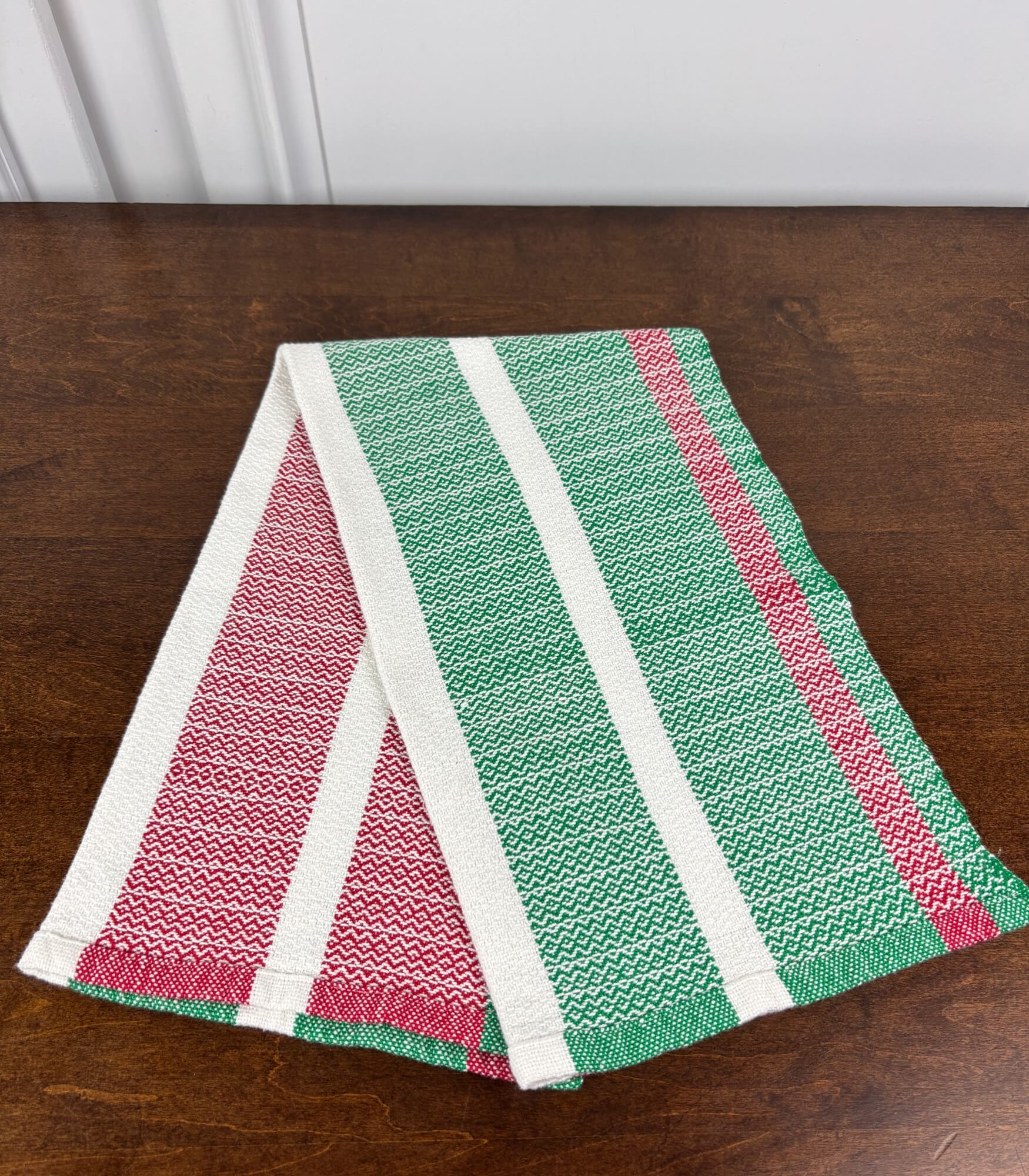 Striped towel with red, green, and white on a wooden surface
