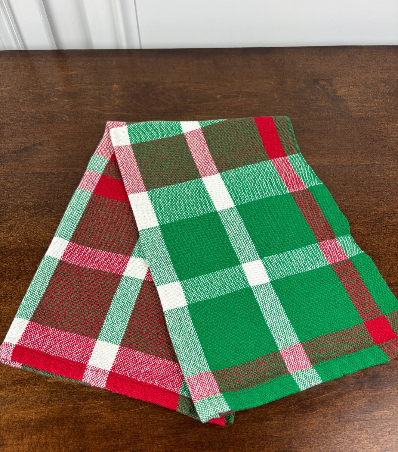 Green, red, and white plaid towel on a wooden surface