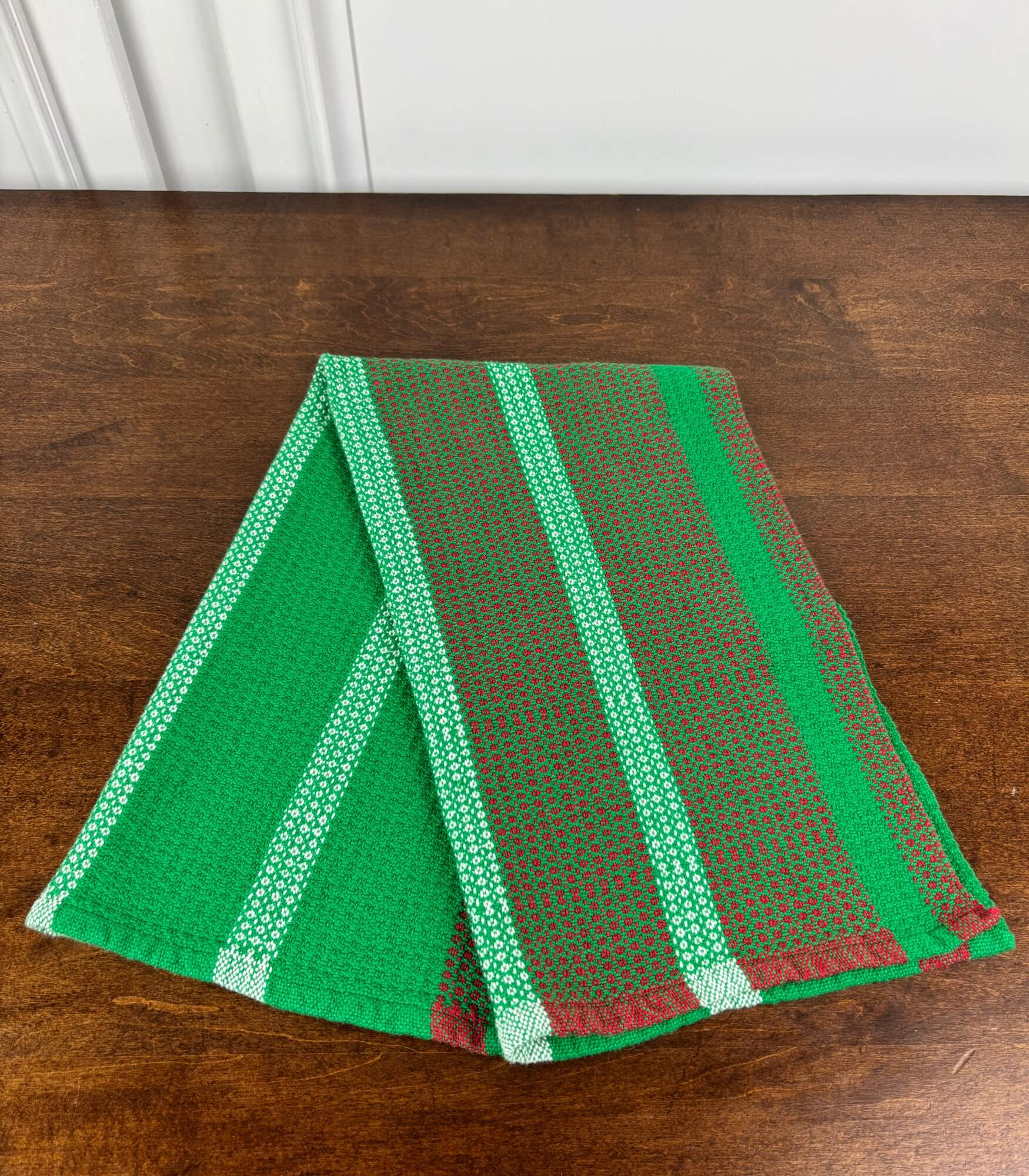 Green, white and red striped towel on a wooden surface