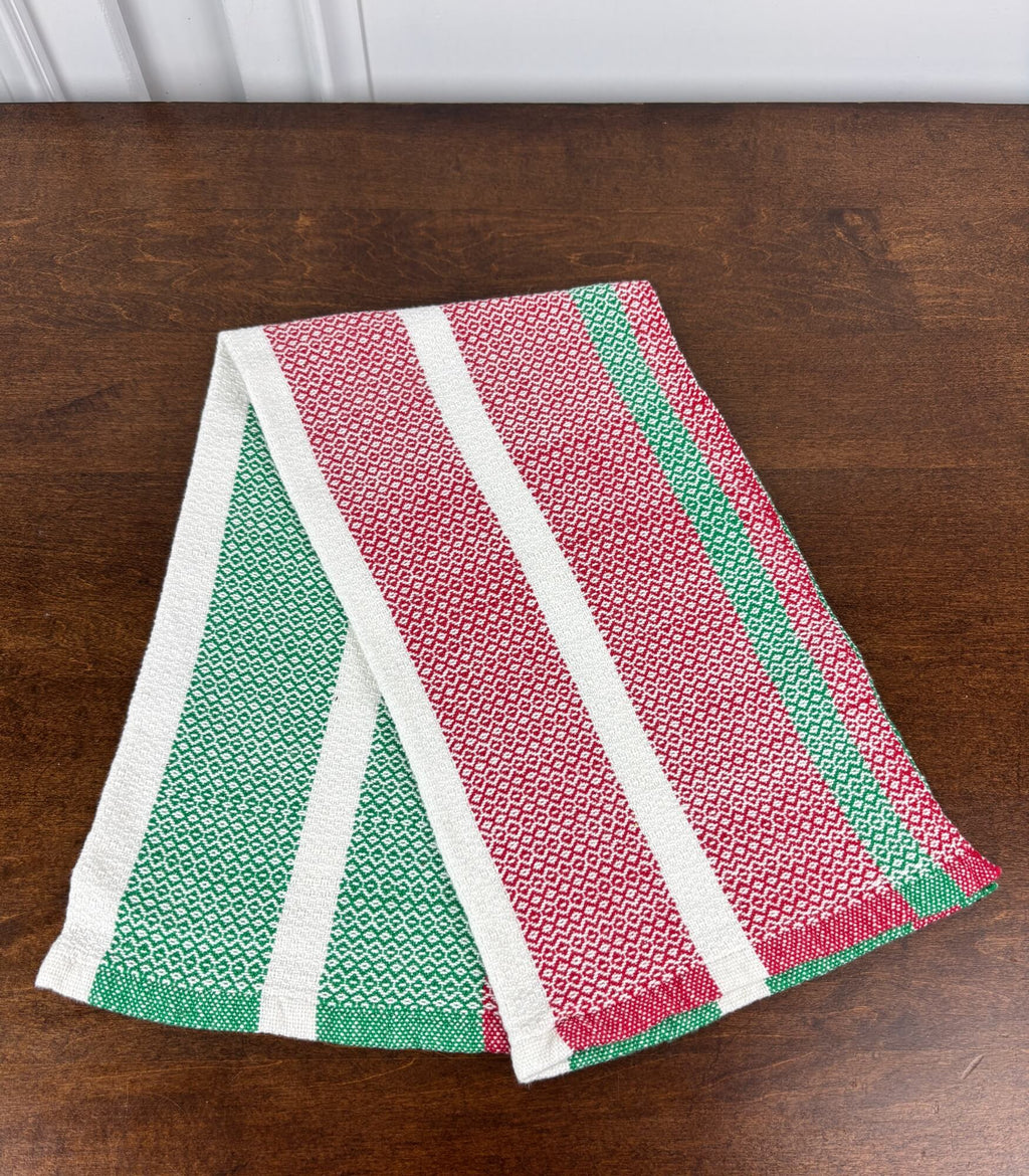 Striped dish towel with green, red, and white pattern on a wooden surface