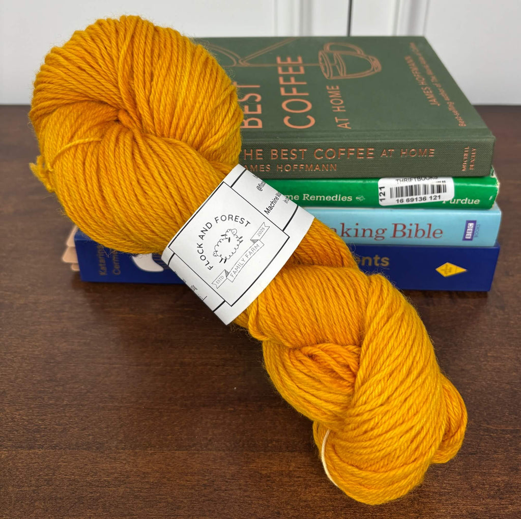 Bright Orange yarn skein with a label on top of books