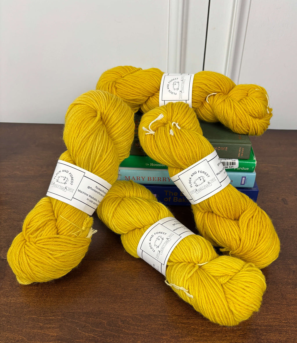 Yellow yarn skeins with labels on a wooden surface