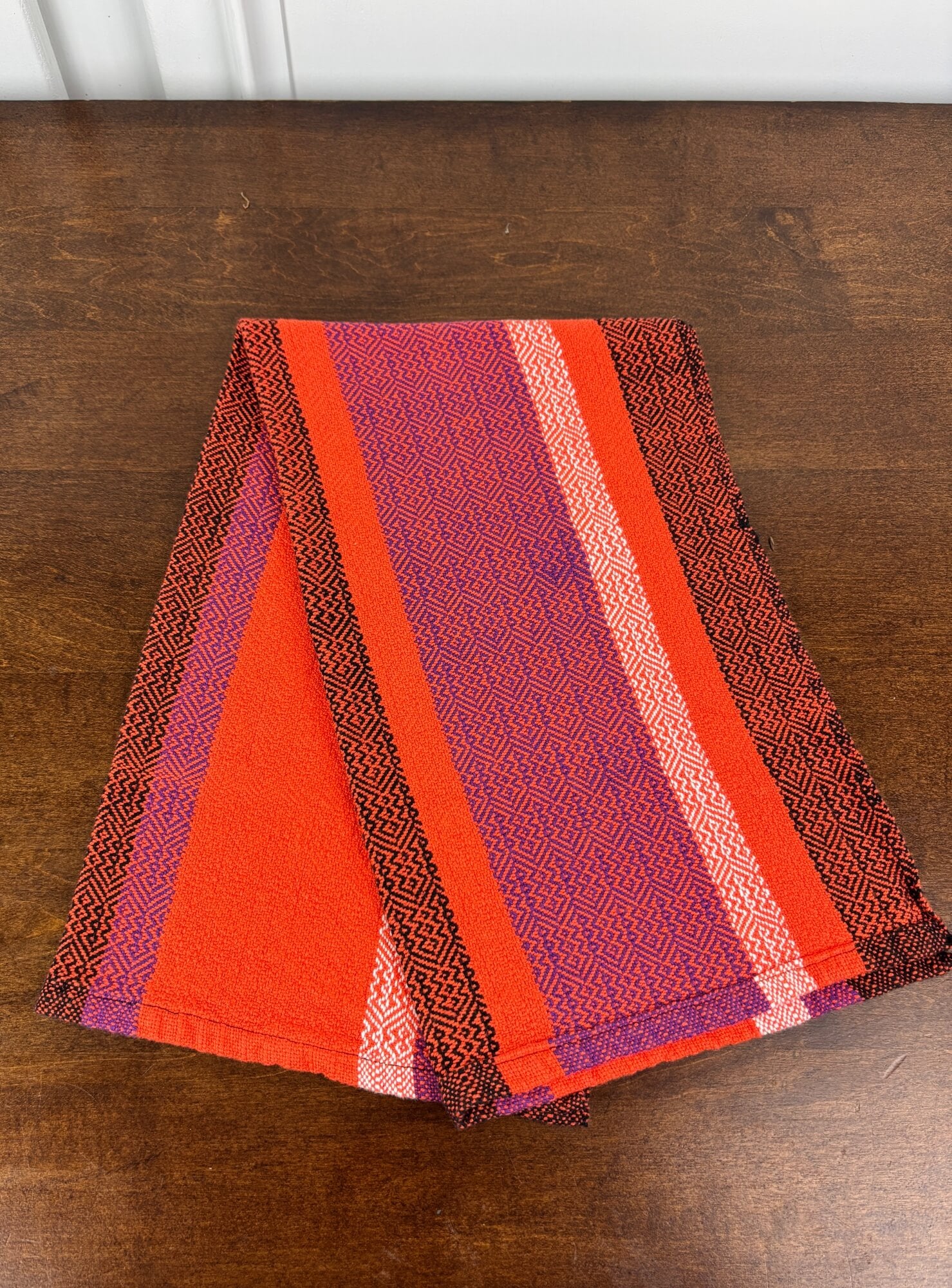 Striped fabric with orange, black and purple patterns on a wooden surface