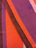 Close-up of fabric with geometric pattern in Orange, purple, and black.