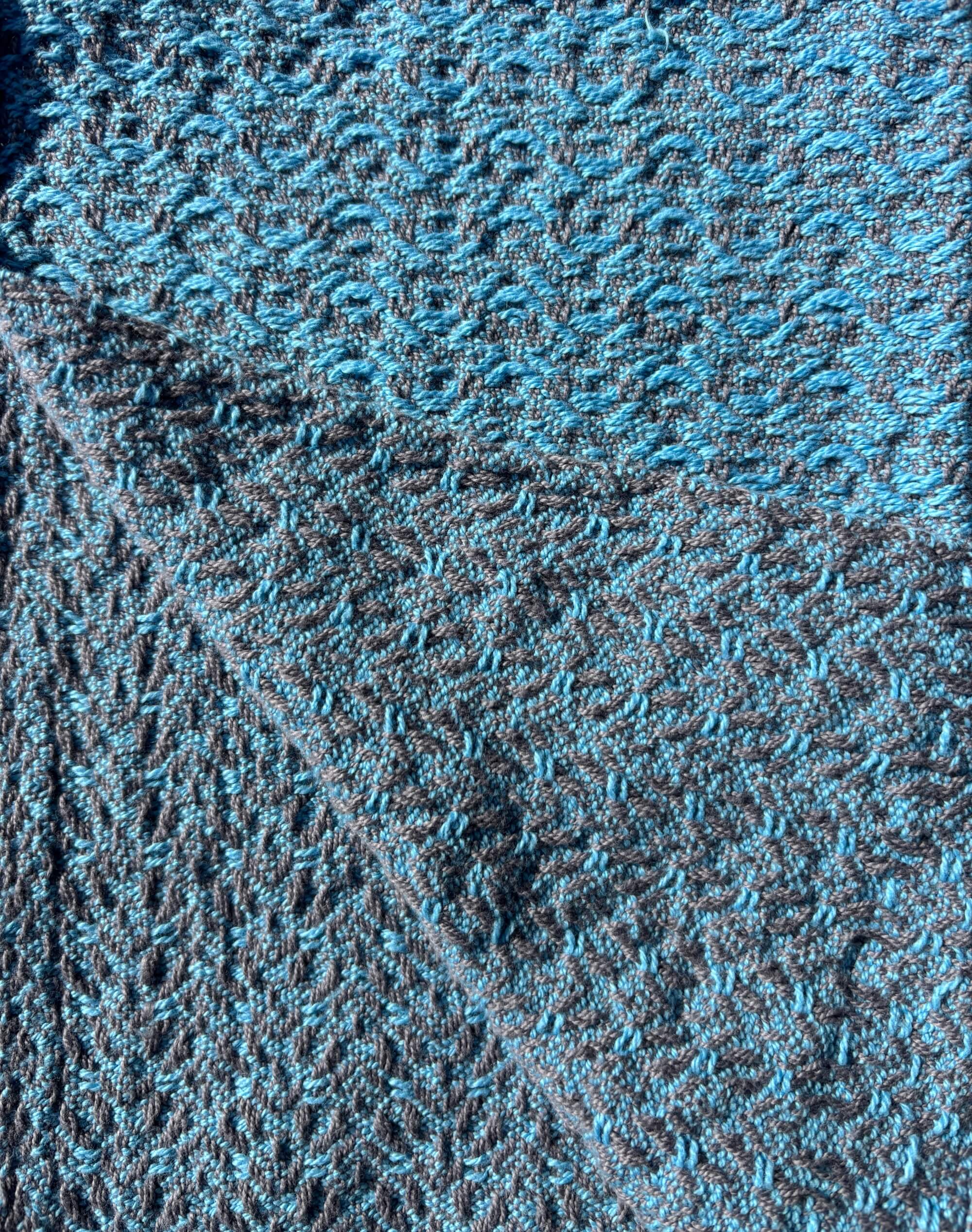 Towel woven with light blue yarn on grey in a brocade pattern