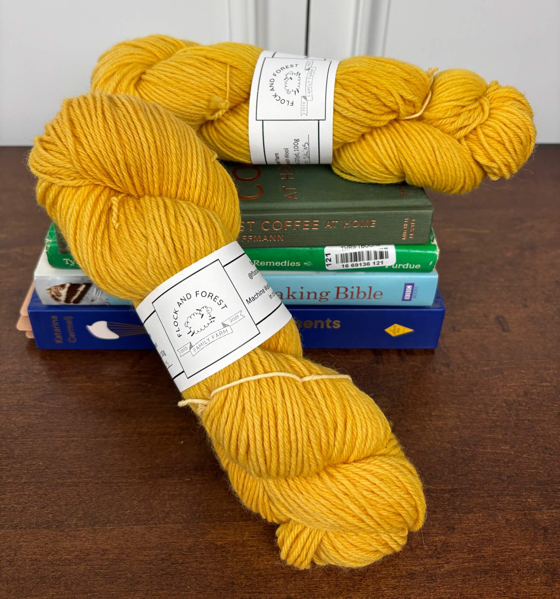Two skeins of orange yarn on a stack of books with labels.