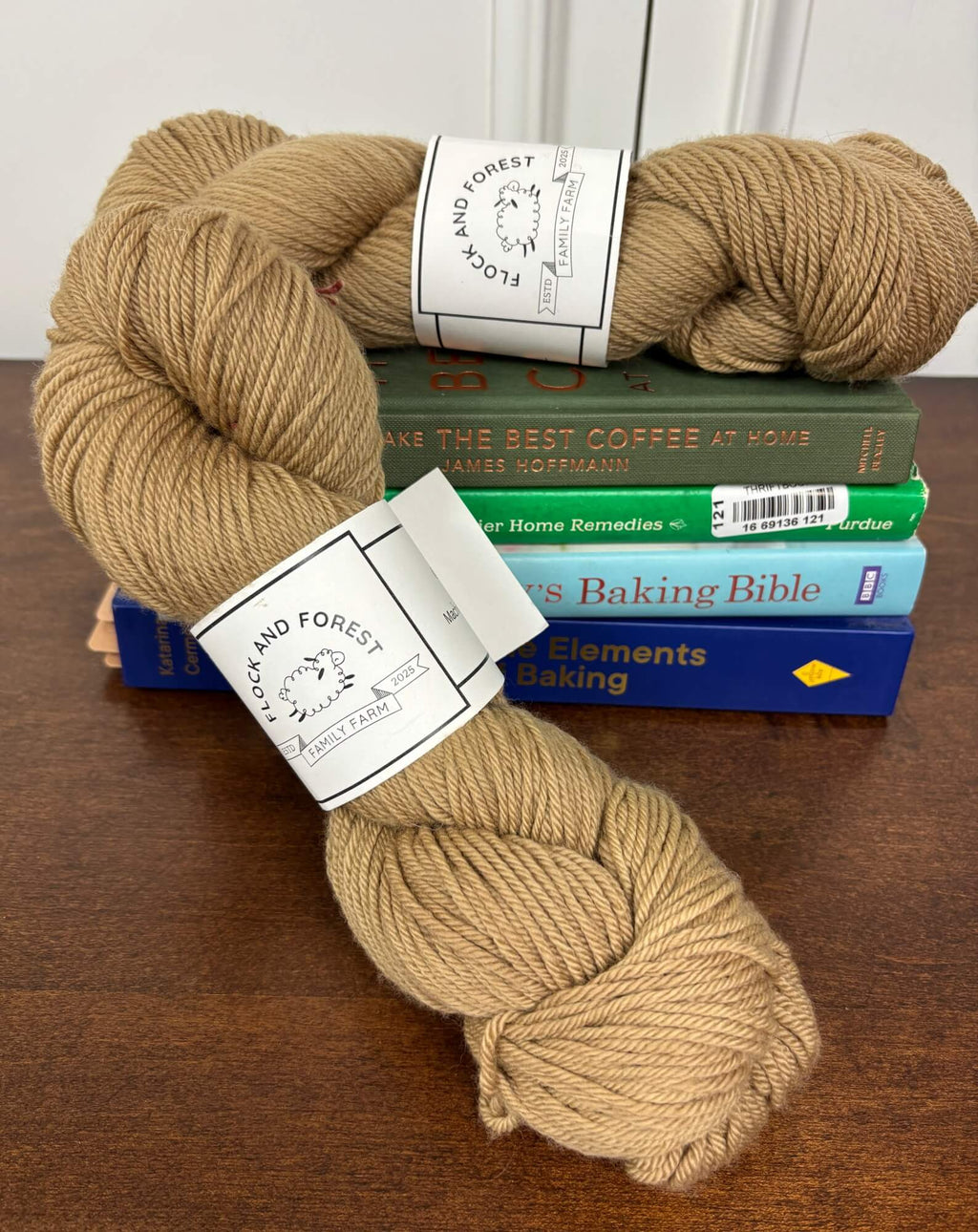 Two skeins of brown yarn with labels on top of books