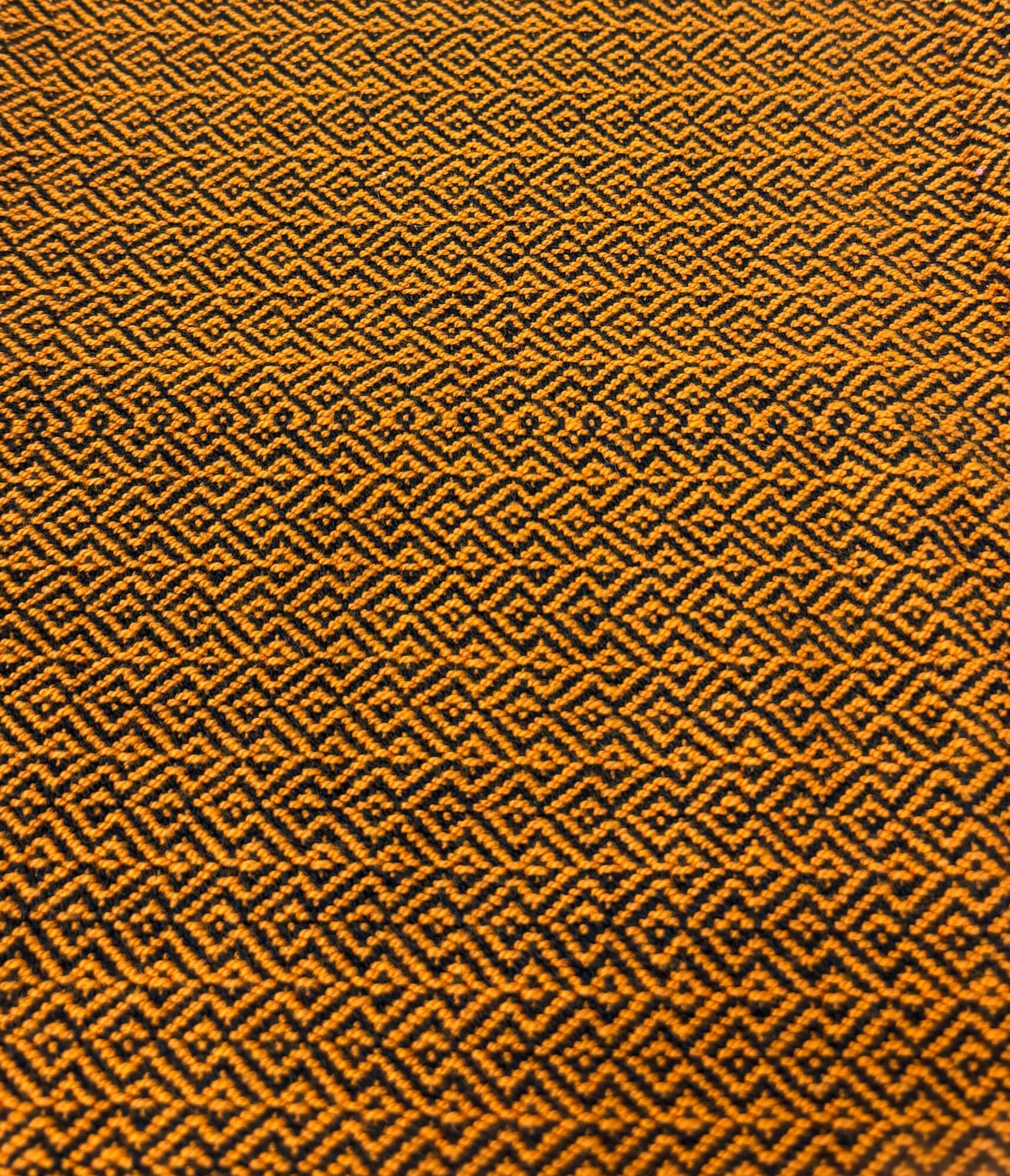 Close-up of a textured orange fabric with a geometric pattern