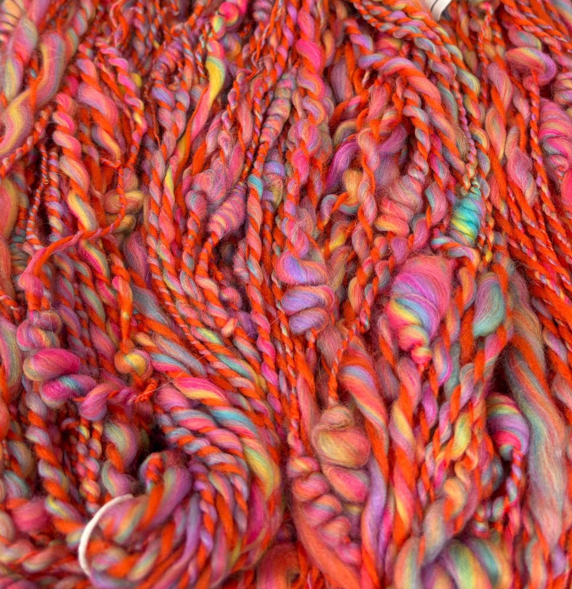 Close-up of orange and rainbow yarn skeins with a focus on texture and color.