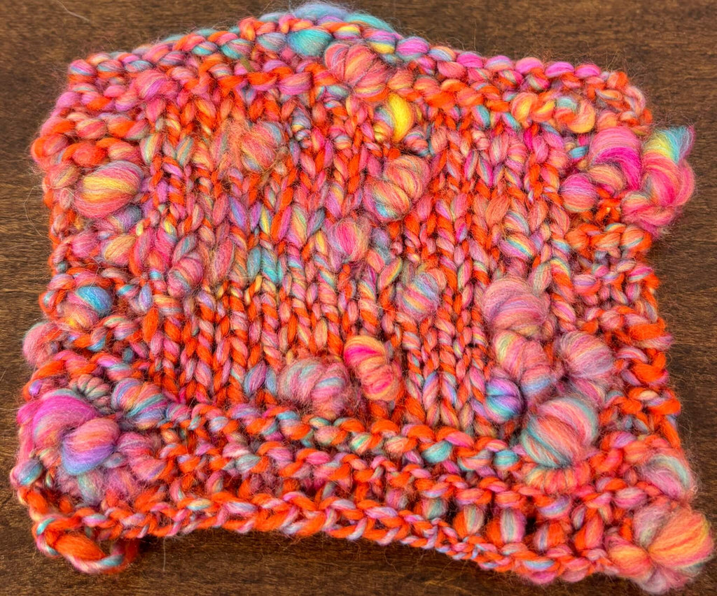 Multicolored knitted fabric swatch on a wooden surface