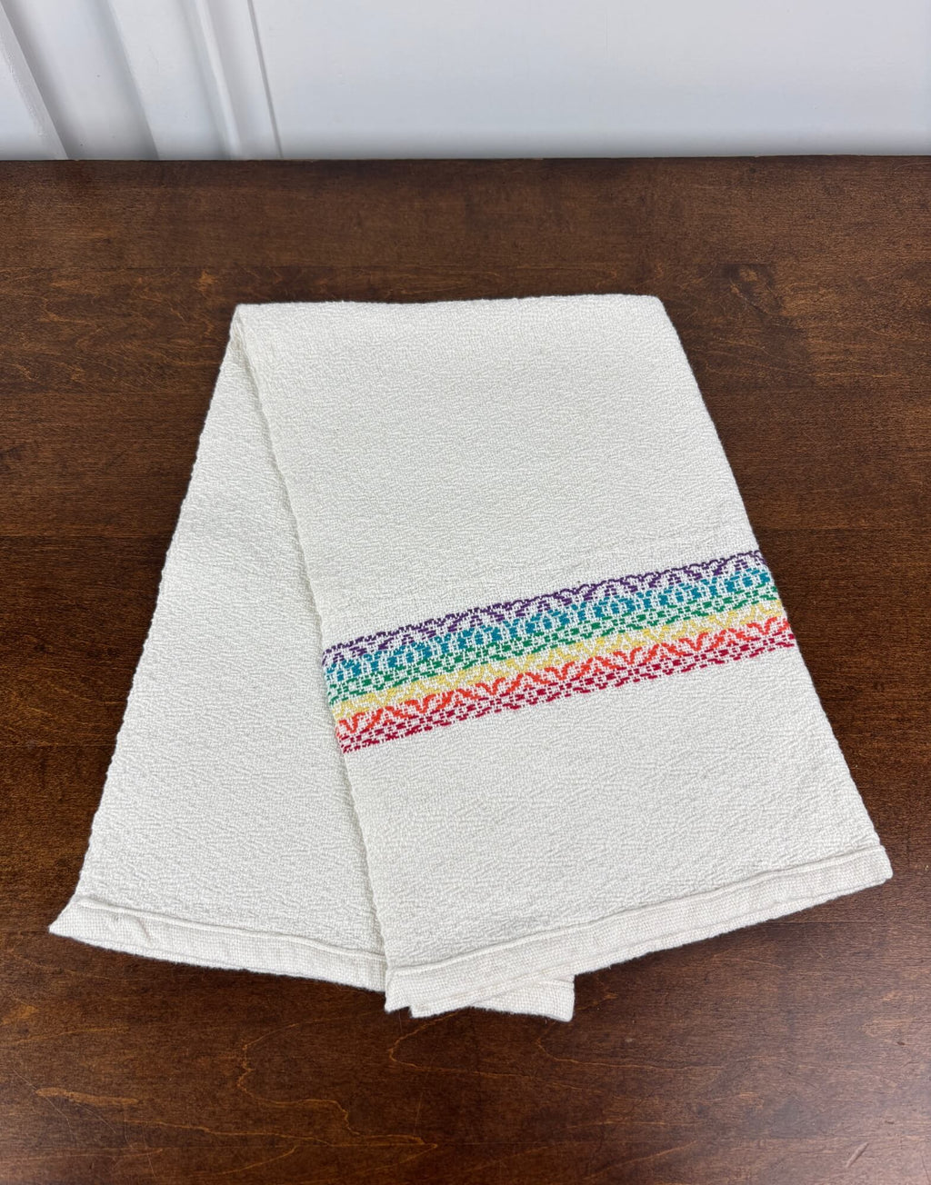 White towel with a Rainbow stripe on a wooden surface