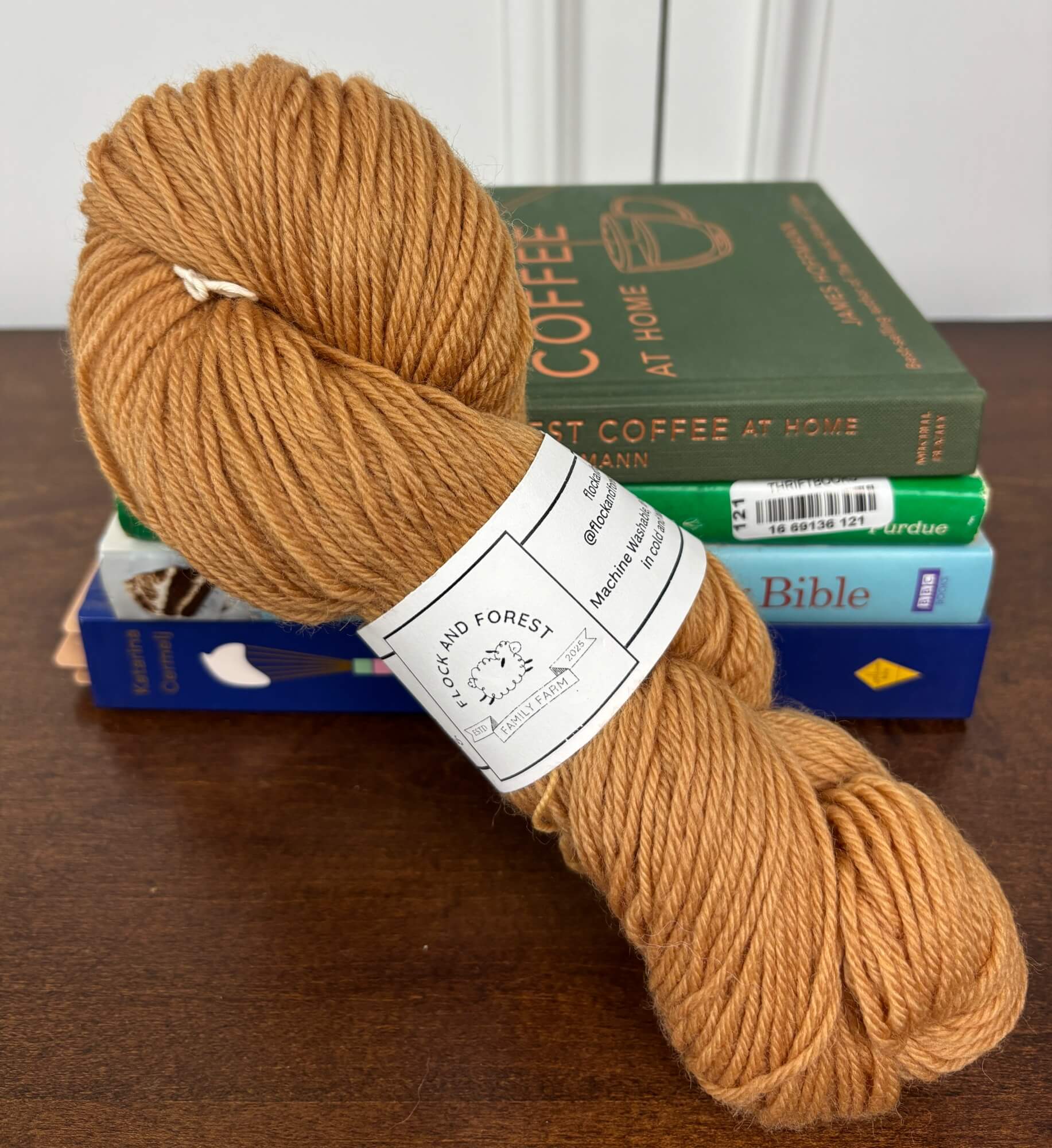 Ball of rusty orange yarn with a label on top of books