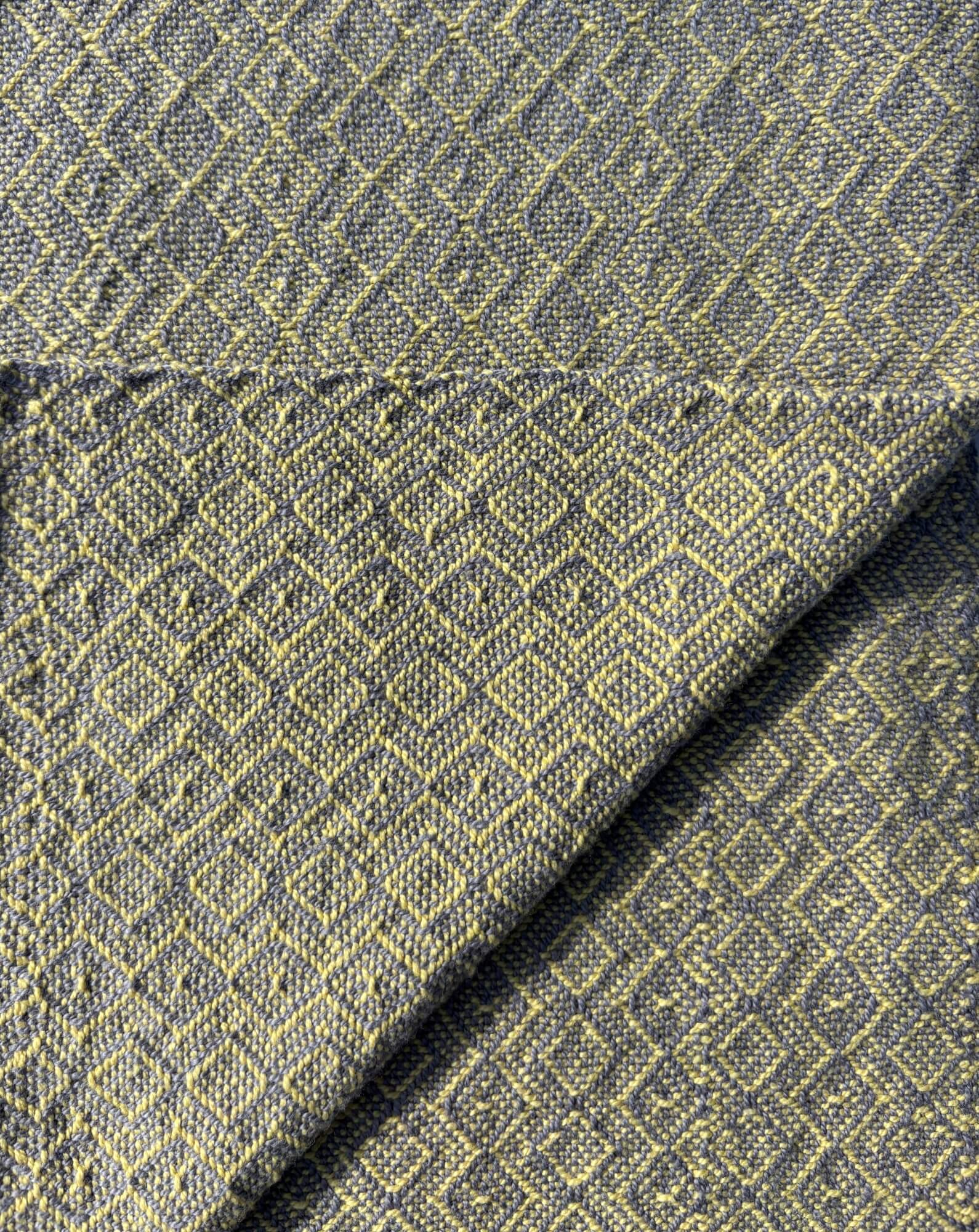 Towel woven in a diamond pattern in yellow on grey